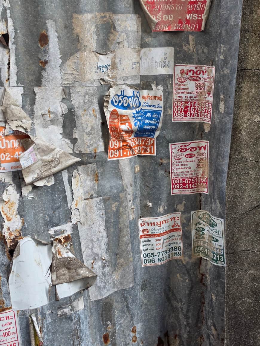 Affichettes superposées sur un poteau peint.