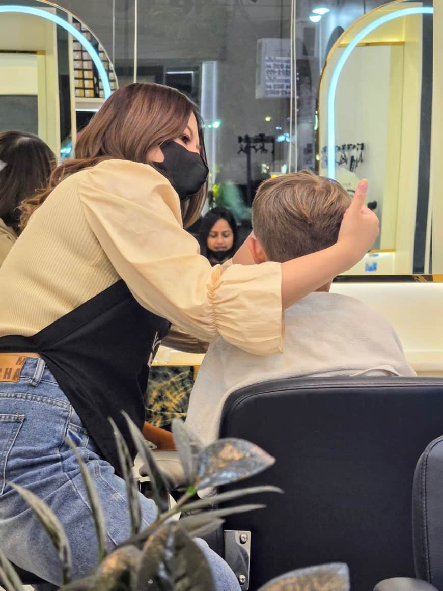 Une adulte et un jeune enfant apparaissent dans le miroir d’un salon.