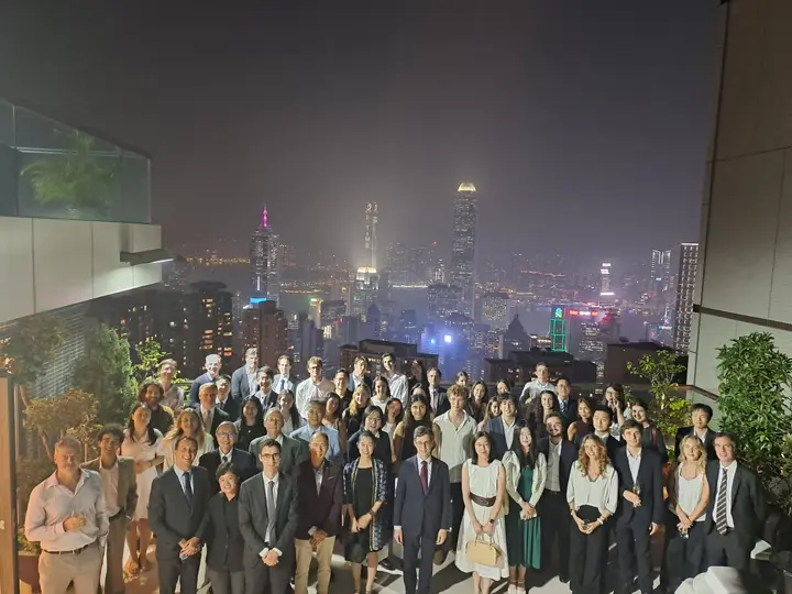Grand groupe posant de nuit sur une terrasse devant un vaste horizon urbain illuminé