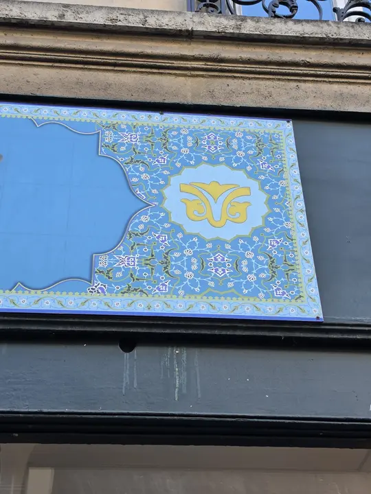 Panneau bleu très orné de rinceaux floraux, portant un emblème doré en son centre