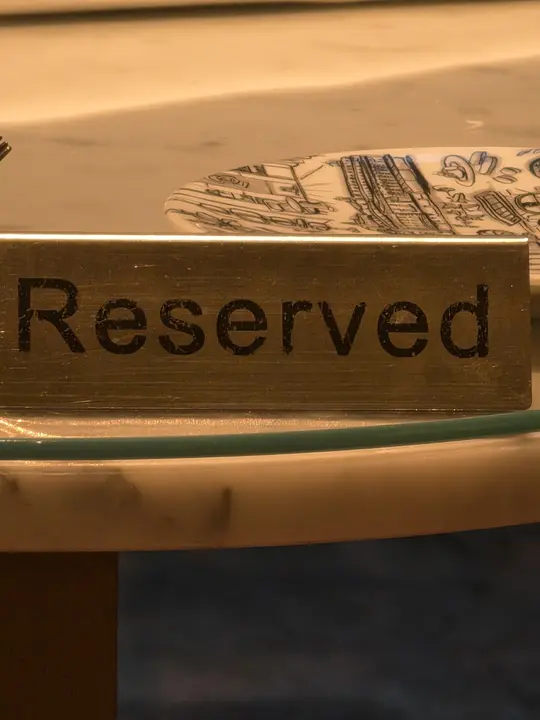 Petit écriteau métallique portant le mot Reserved sur une table
