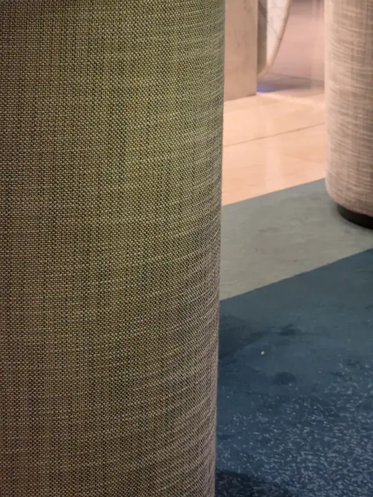 Très gros plan d’un textile vert aux fils serrés, devant une surface bleue