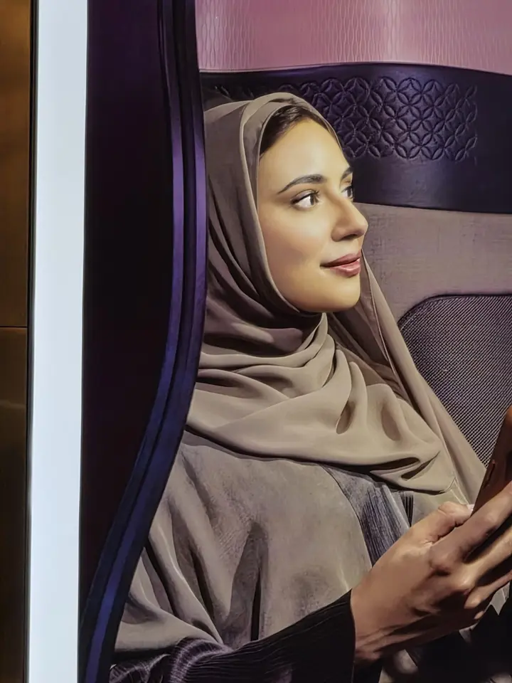 Affiche montrant une femme voilée assise, tenant un appareil et regardant hors champ.