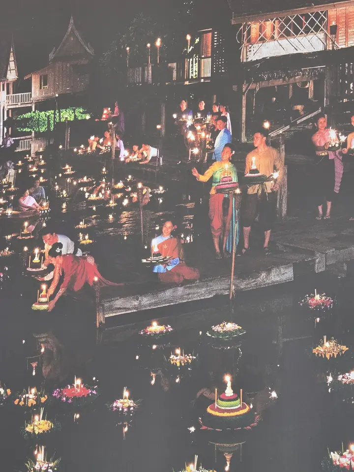 Écran montrant de nuit un marché sur l’eau parcouru de barques et de lumières.