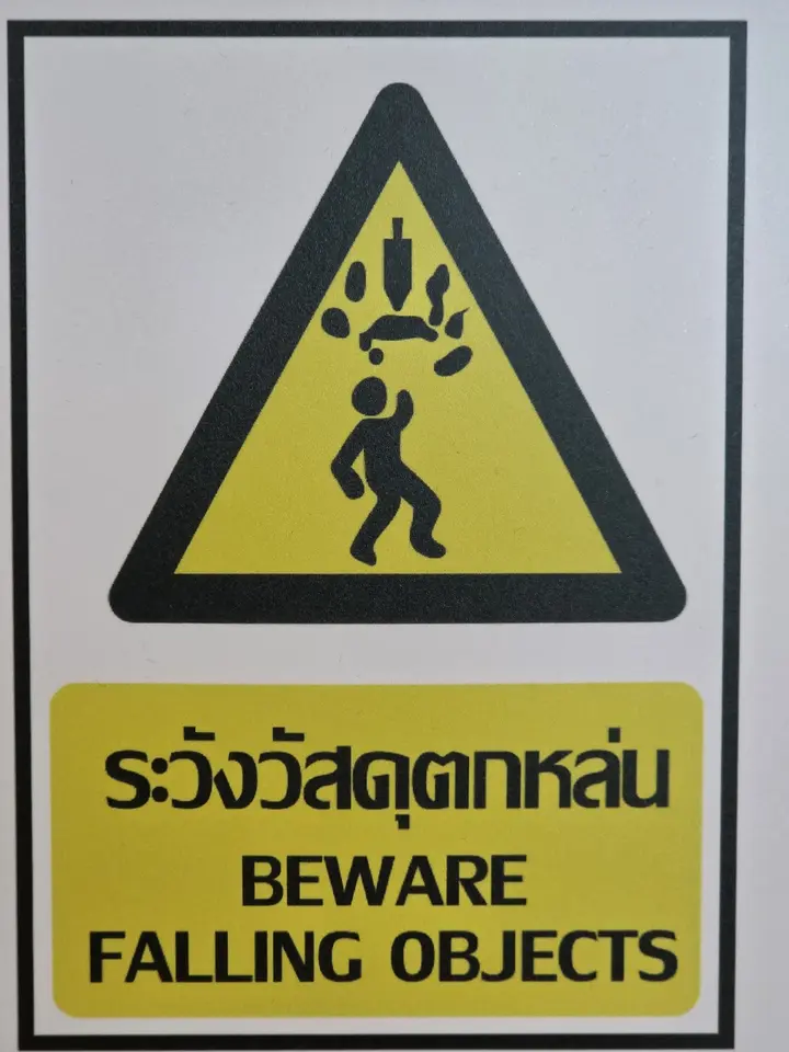 Pictogramme jaune et noir avertissant en thaï et en anglais de la chute d’objets.