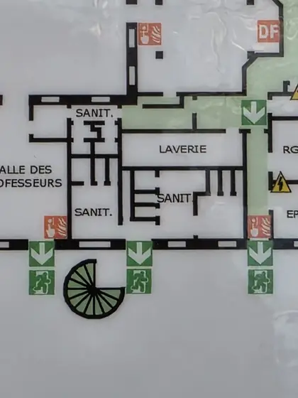 Fragment de plan d’évacuation où couloirs, sanitaires et laverie forment une grille.