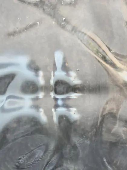 Reflets pâles et déformés de véhicules sur une surface métallique.