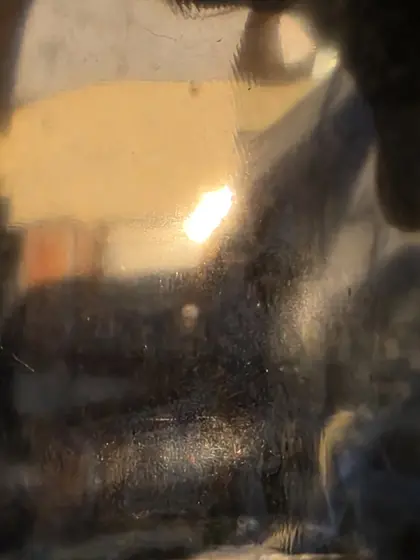 Reflet très déformé et sombre d’un paysage urbain traversé par une lumière chaude.