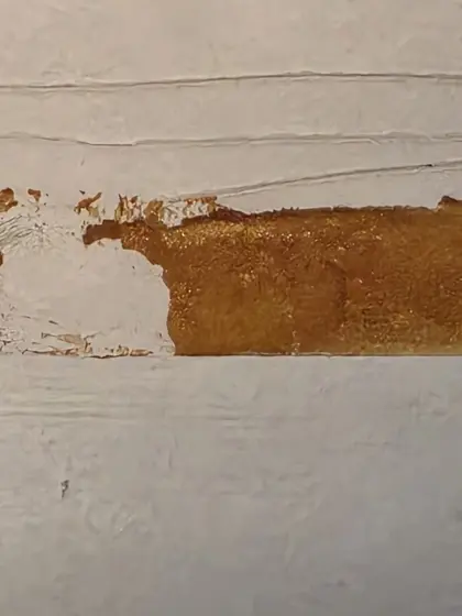 Surface blanche traversée par une bande brune irrégulière.