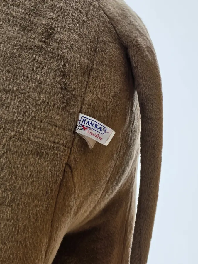Gros plan du corps textile de l’animal de peluche montrant une étiquette HANSA cousue dans le pelage.